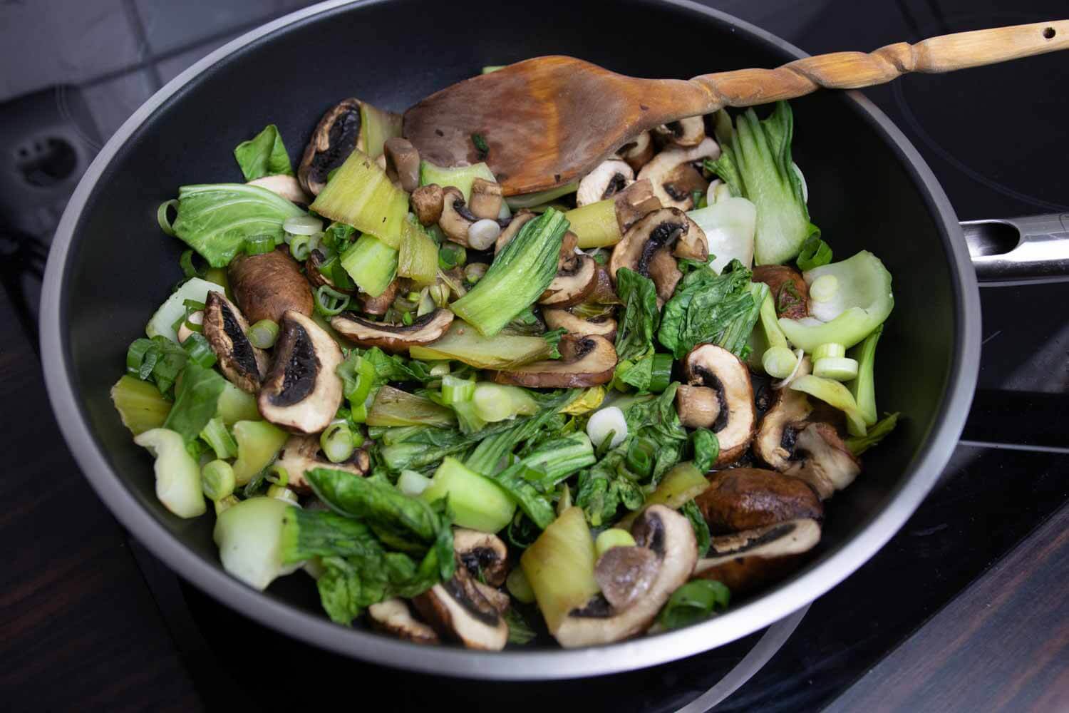 Pak Choi und braune Champignons werden in einer Pfanne gegart